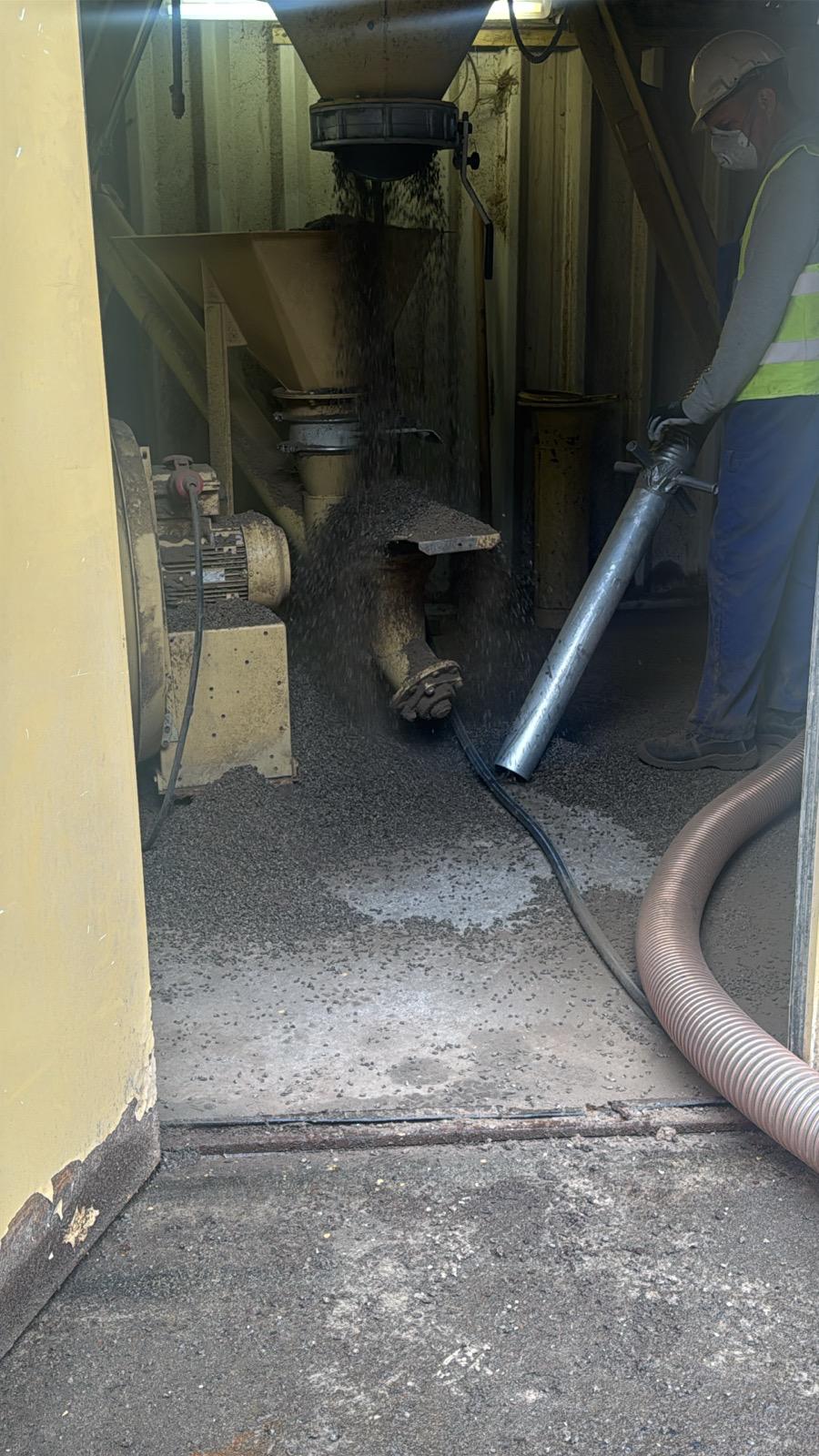 Schlauch an einer Industrieanlage, Material fällt aus dem Trichter